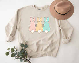 a sweater with three rabbits on it next to a hat