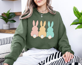 a woman sitting on a couch wearing a sweatshirt with three bunnies on it