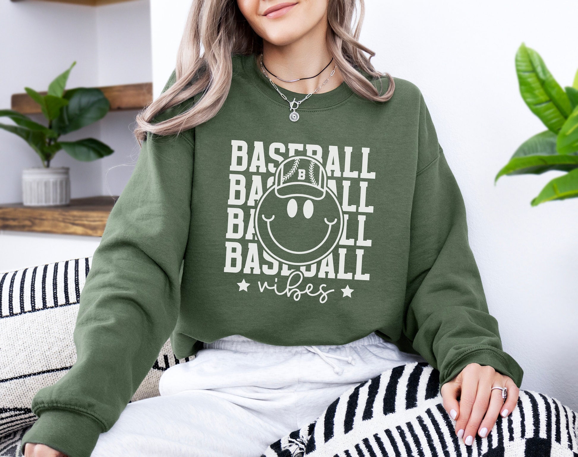 a woman sitting on a couch wearing a baseball sweatshirt