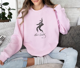 a woman sitting on a couch wearing a pink sweatshirt