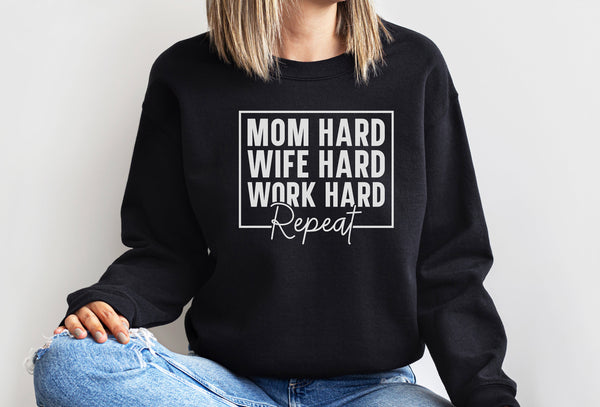 a woman wearing a black sweatshirt that says mom hard, wife hard, work hard