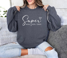 a woman sitting on a couch holding up a sweatshirt