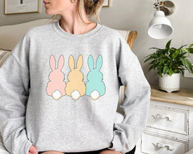 a woman sitting on a couch wearing a sweatshirt with three bunnies on it