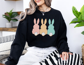 a woman sitting on a couch wearing a black sweater with three bunnies on it