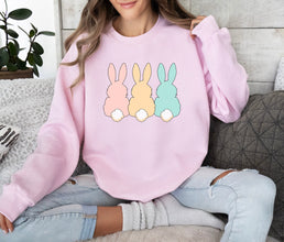 a woman sitting on a couch wearing a pink sweatshirt with three bunnies on it