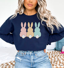 a woman with blonde hair wearing a blue sweatshirt with three bunnies on it