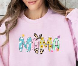 a woman sitting on a couch wearing a pink sweatshirt with the word mama printed on