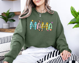 a woman sitting on a couch wearing a sweatshirt that says mama