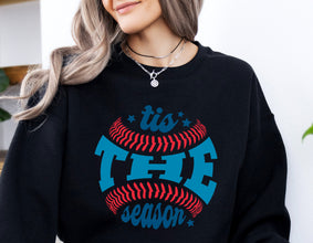 a woman sitting on a couch wearing a black sweatshirt with a red and blue baseball