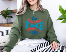 a woman sitting on a couch wearing a green sweatshirt