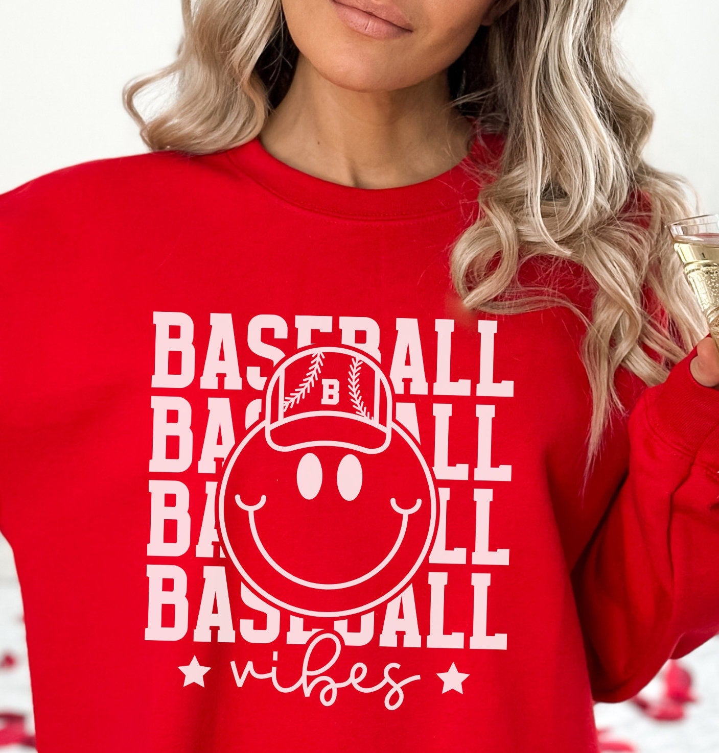 a woman in a red baseball sweatshirt holding a glass of champagne